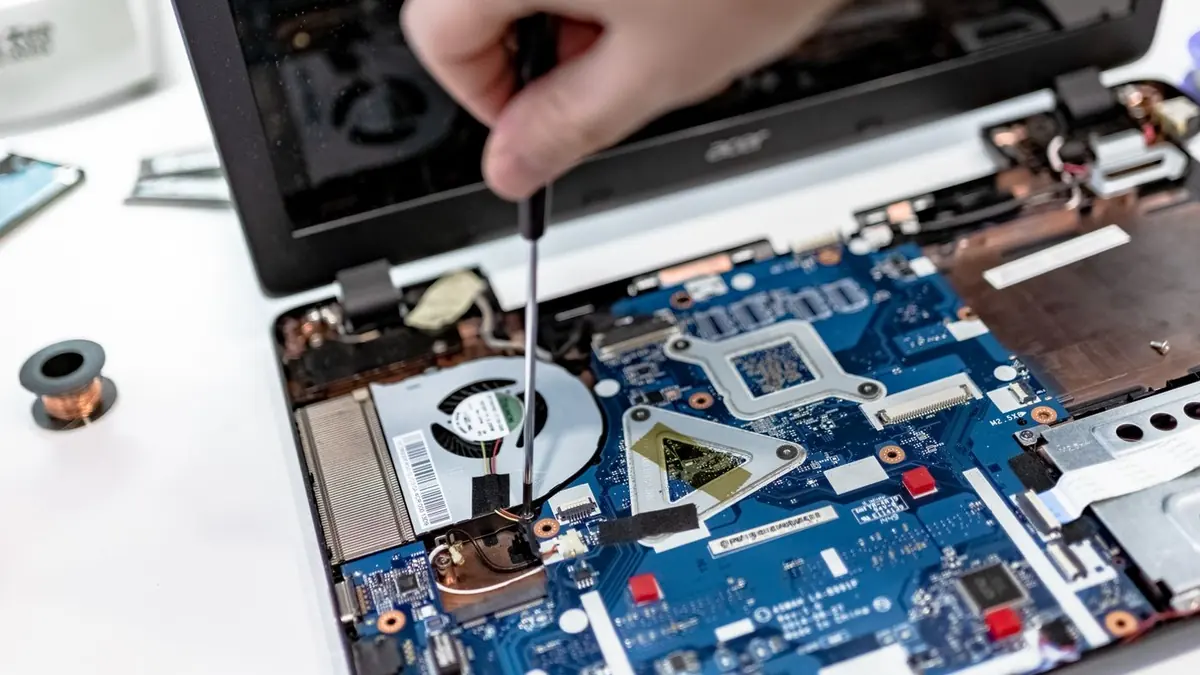 Técnico reparando la placa de un notebook abierto con un destornillador